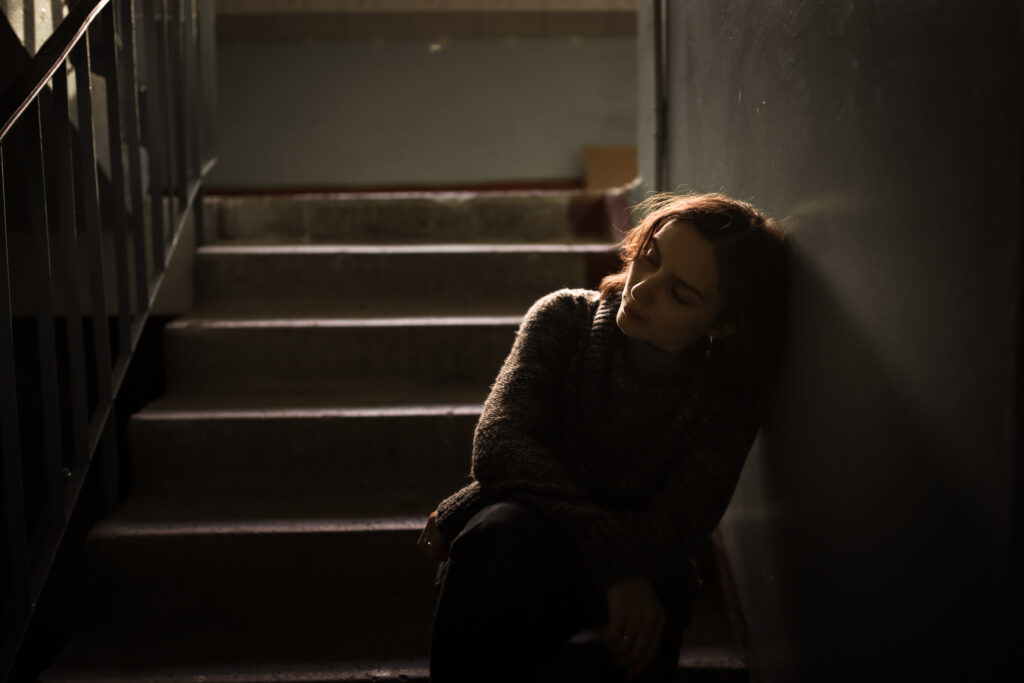 A woman sits in a stairwell, in need of depression treatment in Bend OR